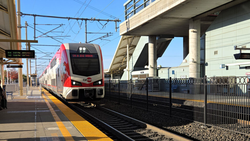 White and red train arriving at train station.