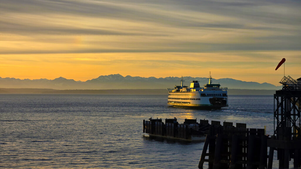 Washington State Ferry departing from the dock in Seattle during the sunset.