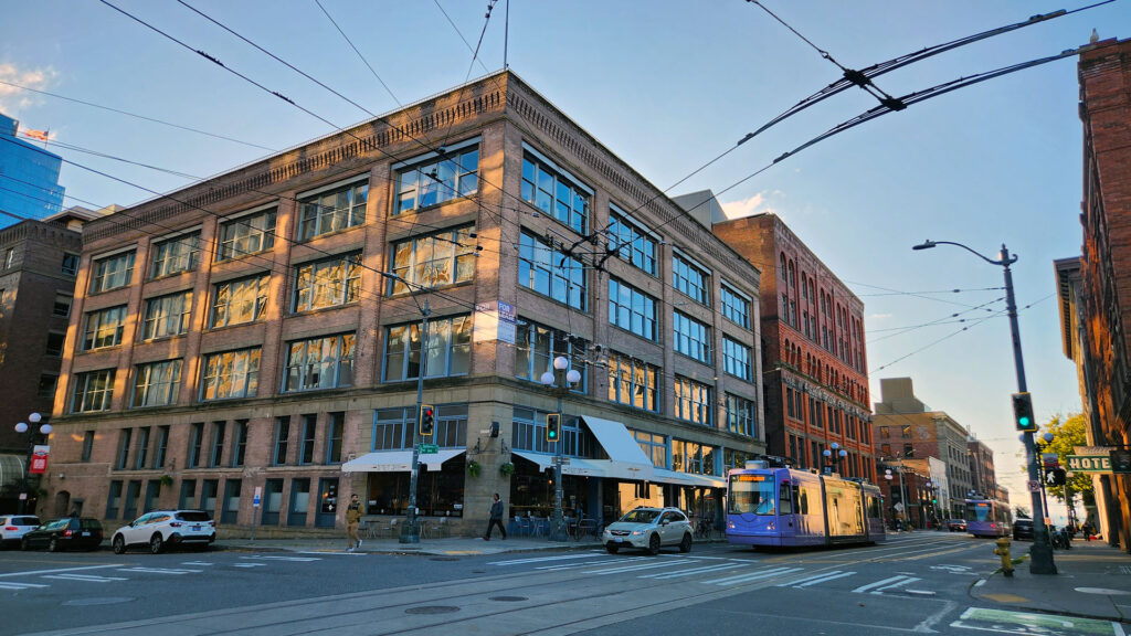 Purple streetcar waiting in front of a five story brick office building.