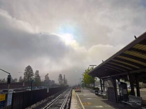 Standing on a train platform with a fog bank breaking with the sun popping out.