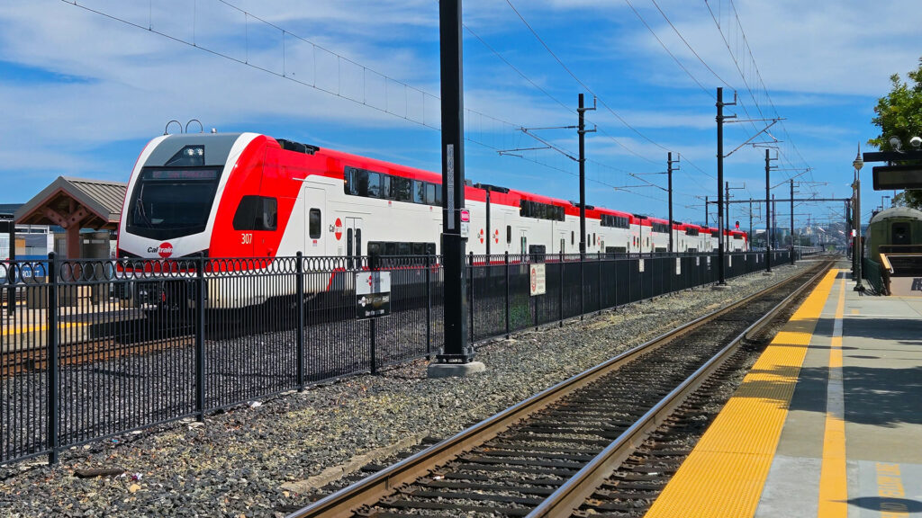 Red and white train arriving at train station.
