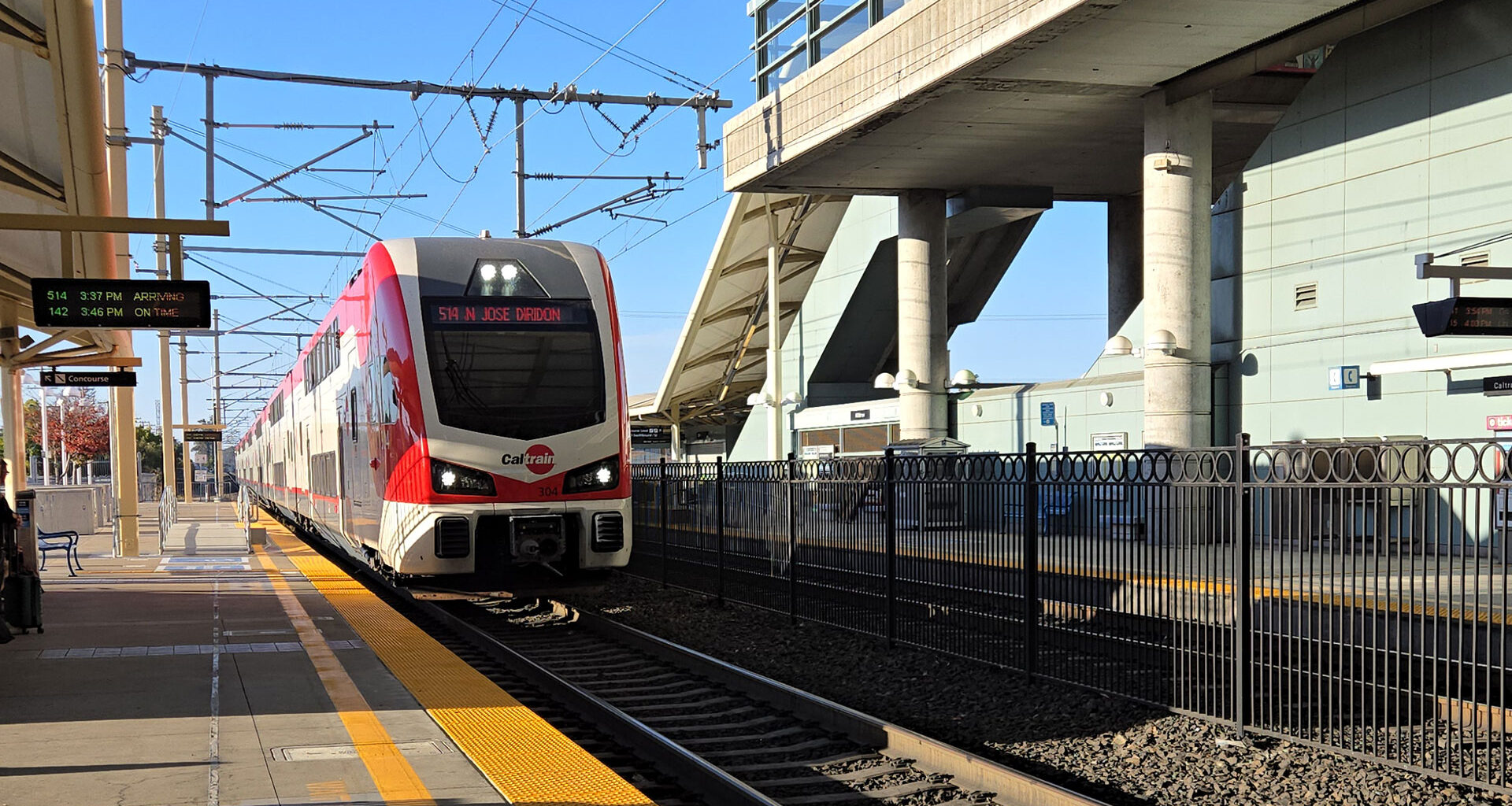 White and red train arriving at train station.