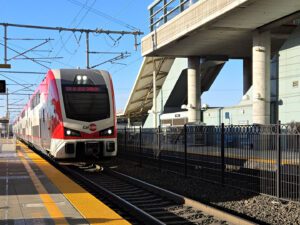 White and red train arriving at train station.