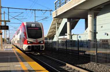 White and red train arriving at train station.