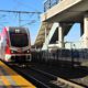White and red train arriving at train station.