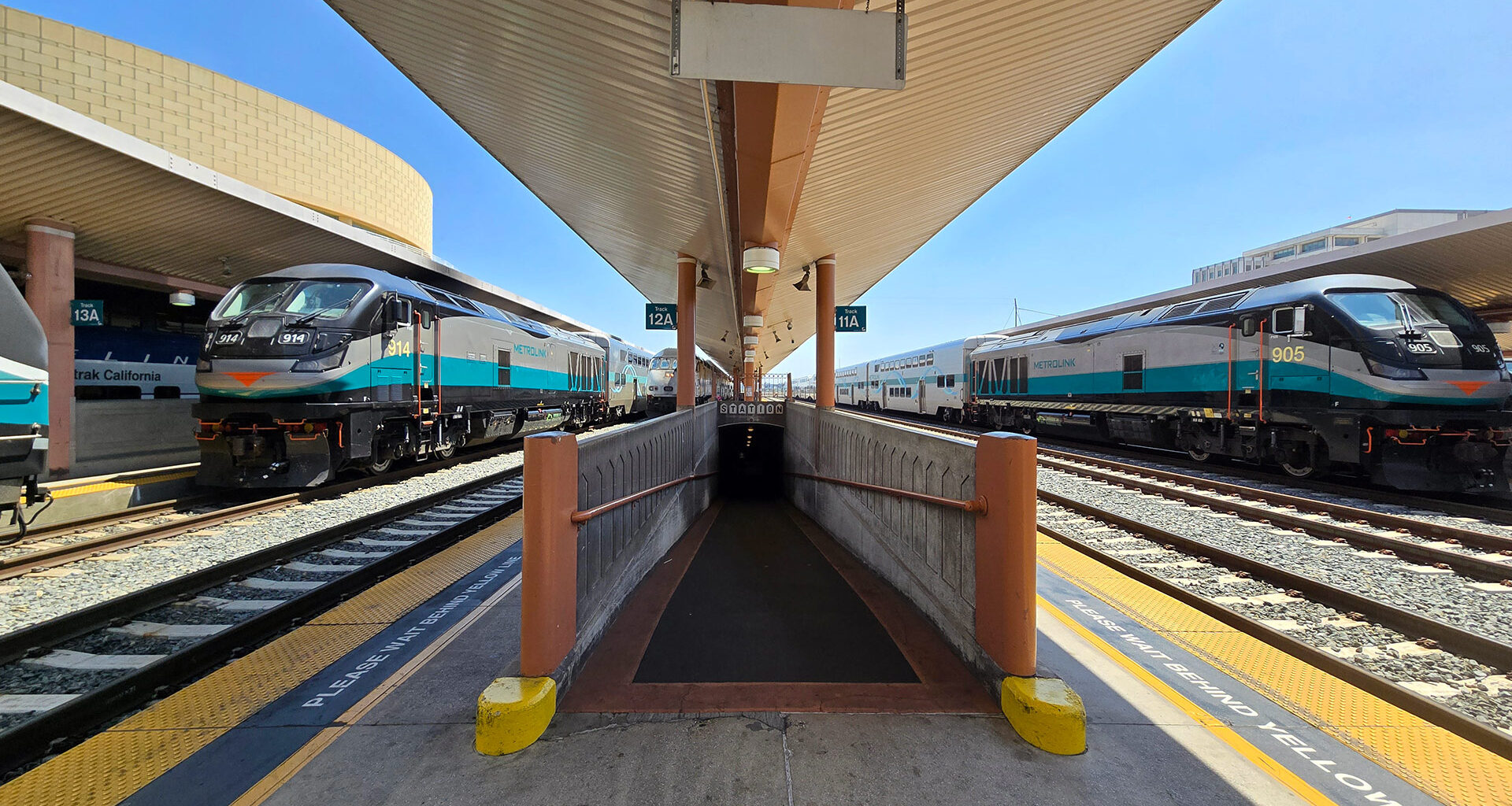 Black, silver, and teal painted trains waiting at a station platform.