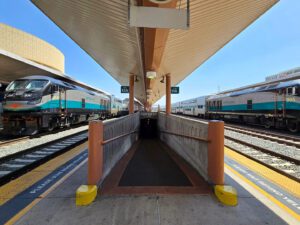 Black, silver, and teal painted trains waiting at a station platform.