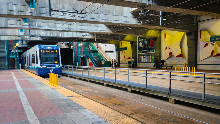 Blue and white light rail train entering the station.