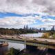 View from an Amtrak train departing Philadelphia, with the skyline and highway bridge visible along the Schuylkill River, representing the rail corridor a future Reading to Philadelphia line would extend.